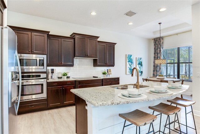 13008 Eagles Entry Dr, Odessa, FL 33556 - kitchen with appliances with stainless steel finishes, a sink, light wood finished floors, recessed lighting, and decorative backsplash