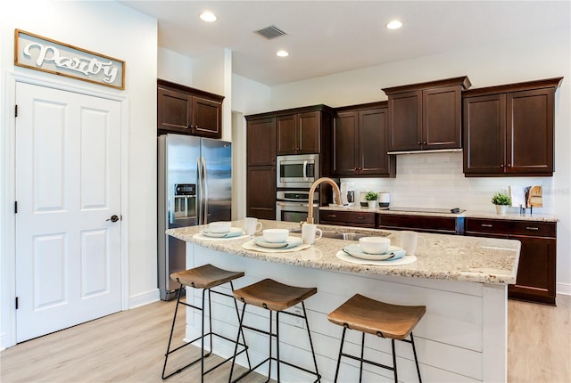 13008 Eagles Entry Dr, Odessa, FL 33556 - kitchen with stainless steel appliances, light wood-type flooring, a sink, dark brown cabinetry, and recessed lighting