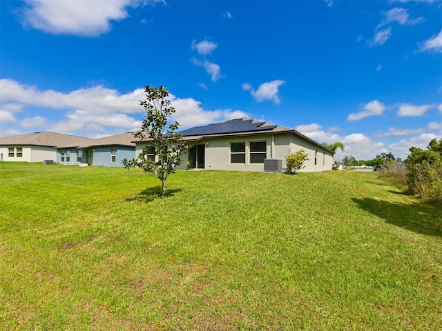 6416 Cobble Bliss St, Zephyrhills, FL 33541 - back of property with a lawn, central AC, roof mounted solar panels, and stucco siding