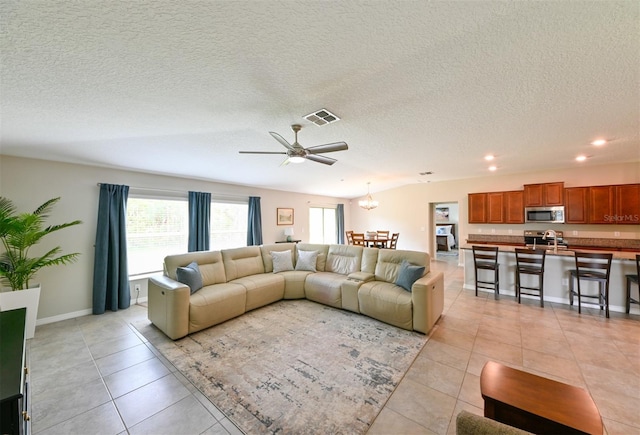 6416 Cobble Bliss St, Zephyrhills, FL 33541 - living area with light tile patterned floors, visible vents, recessed lighting, and ceiling fan with notable chandelier
