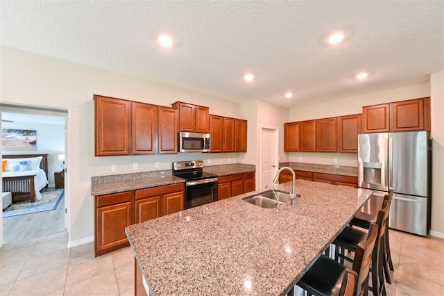6416 Cobble Bliss St, Zephyrhills, FL 33541 - kitchen with a sink, a kitchen bar, appliances with stainless steel finishes, brown cabinets, and a kitchen island with sink