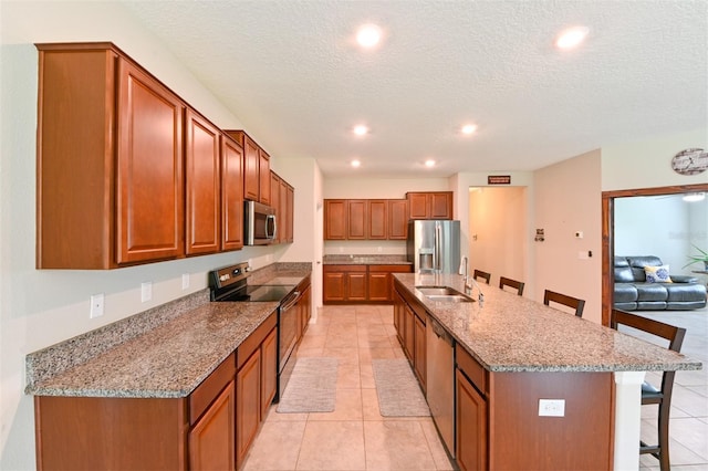 6416 Cobble Bliss St, Zephyrhills, FL 33541 - kitchen featuring a breakfast bar, stainless steel appliances, a sink, stone countertops, and brown cabinetry