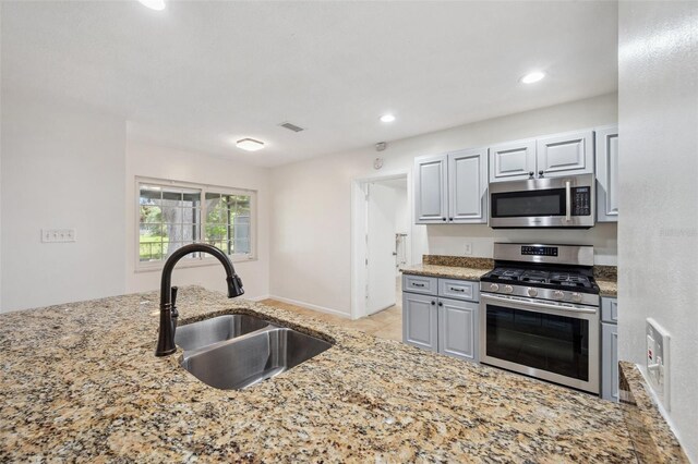 1308 W Perdiz St, Tampa, FL 33612 - kitchen with light stone countertops, stainless steel appliances, visible vents, and a sink