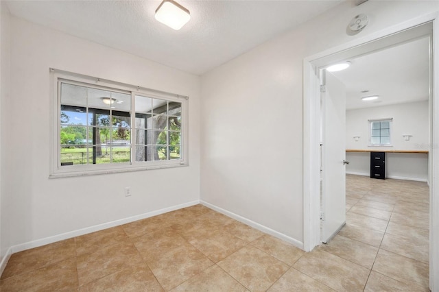 1308 W Perdiz St, Tampa, FL 33612 - unfurnished room with a wealth of natural light, light tile patterned flooring, a textured ceiling, and baseboards