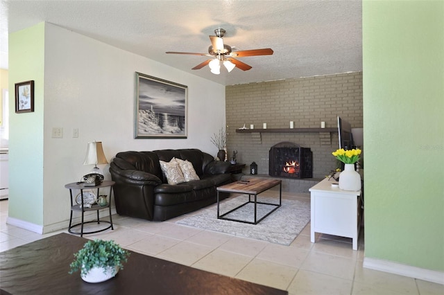 living area featuring a fireplace, a textured ceiling, ceiling fan, and tile patterned flooring