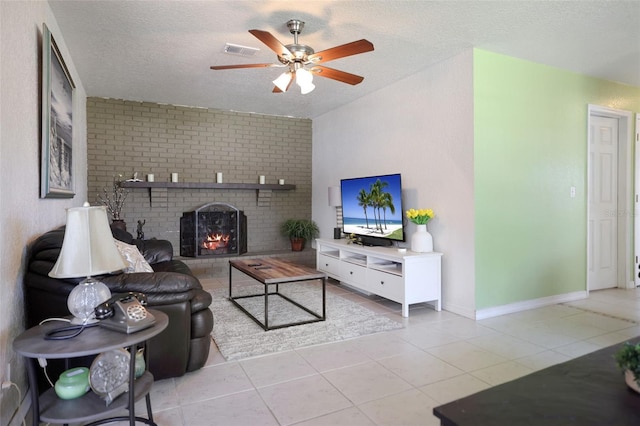 living room with a textured ceiling, light tile patterned flooring, visible vents, a ceiling fan, and a fireplace