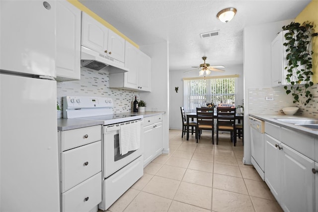 kitchen featuring white appliances, light tile patterned floors, under cabinet range hood, visible vents, and white cabinets