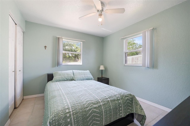 bedroom with multiple windows, a closet, baseboards, and light tile patterned floors
