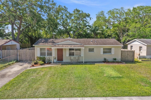 view of front of home with brick siding, fence, a front lawn, and concrete driveway
