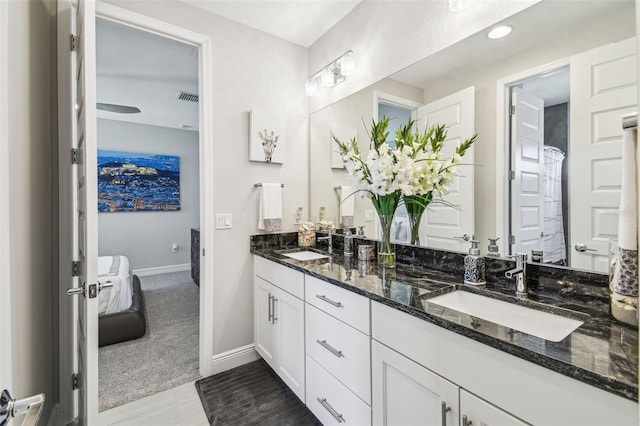 bathroom featuring double vanity, visible vents, a sink, and baseboards