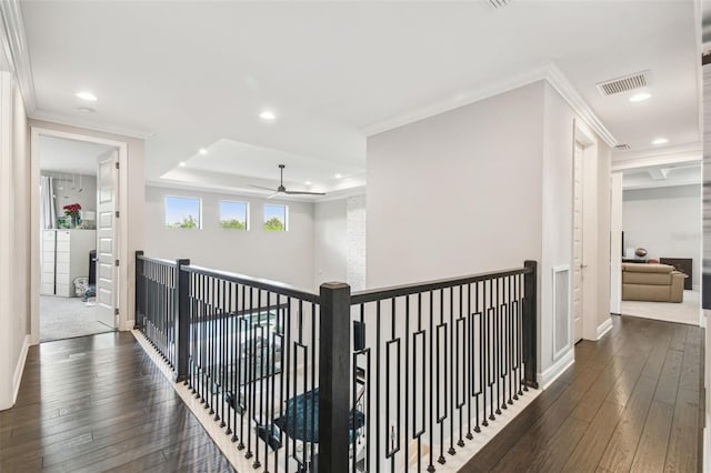 corridor featuring dark wood-type flooring, a tray ceiling, visible vents, recessed lighting, and baseboards