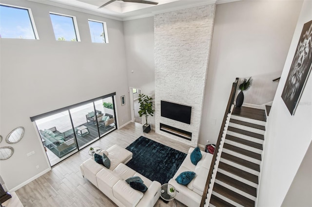 living area with wood finished floors, a fireplace, ornamental molding, and plenty of natural light