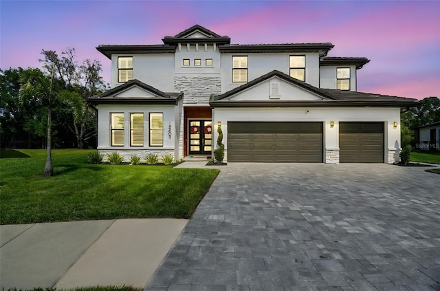modern home with stucco siding, decorative driveway, a front yard, a tile roof, and a garage