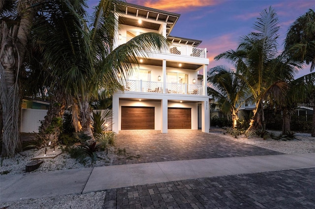 311 Spring Ave, Anna Maria, FL 34216 - view of front of house with a balcony, decorative driveway, stucco siding, and an attached garage