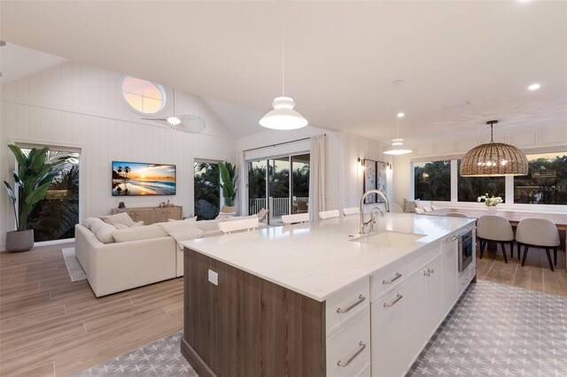 311 Spring Ave, Anna Maria, FL 34216 - kitchen featuring open floor plan, white cabinetry, decorative light fixtures, a sink, and an island with sink