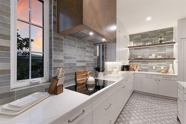 311 Spring Ave, Anna Maria, FL 34216 - kitchen with light countertops, backsplash, premium range hood, black electric stovetop, and white cabinets