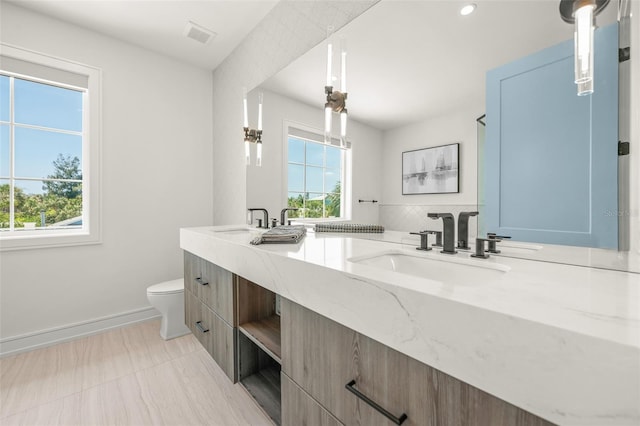 311 Spring Ave, Anna Maria, FL 34216 - bathroom with toilet, a sink, double vanity, and a healthy amount of sunlight