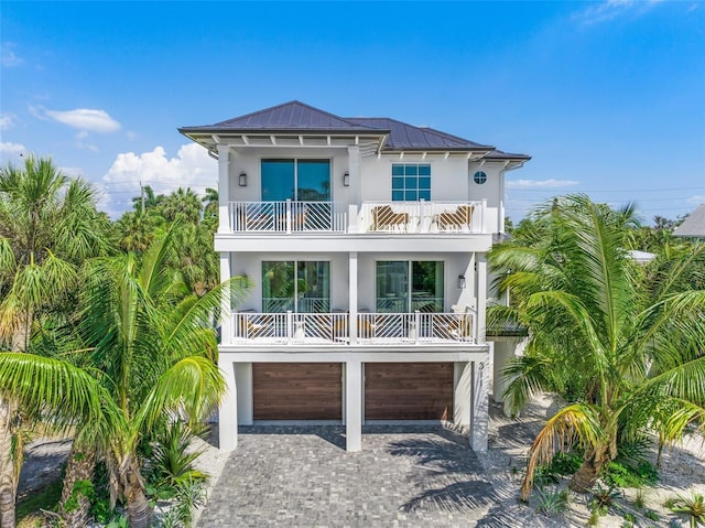 311 Spring Ave, Anna Maria, FL 34216 - view of front facade with stucco siding, metal roof, a balcony, decorative driveway, and a garage