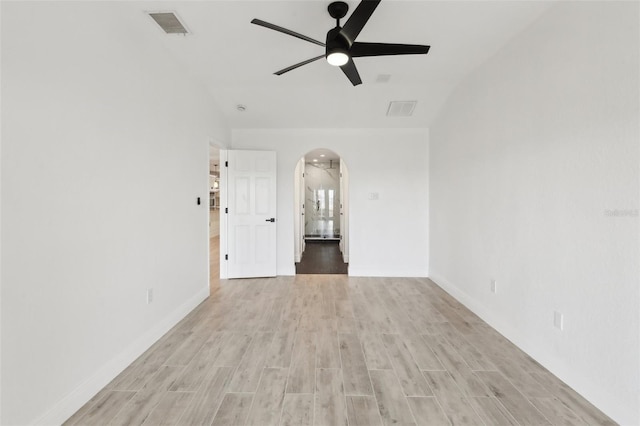 empty room featuring arched walkways, light wood finished floors, visible vents, and a ceiling fan