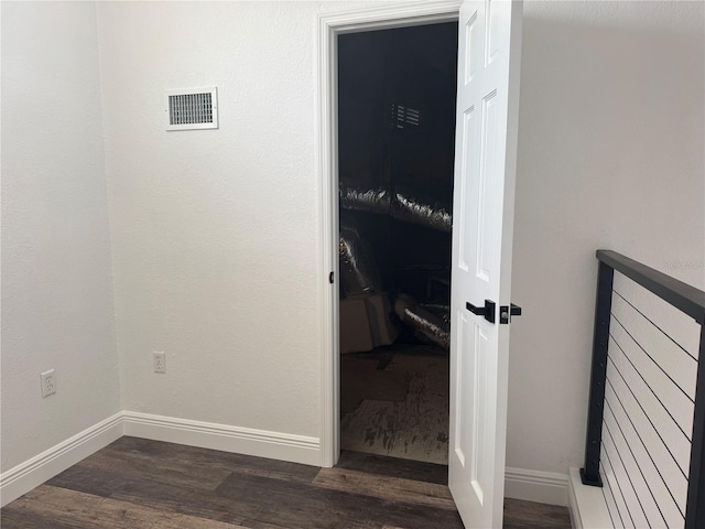 corridor with visible vents, baseboards, and dark wood finished floors