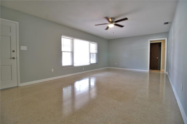 empty room featuring light speckled floor, visible vents, baseboards, and ceiling fan