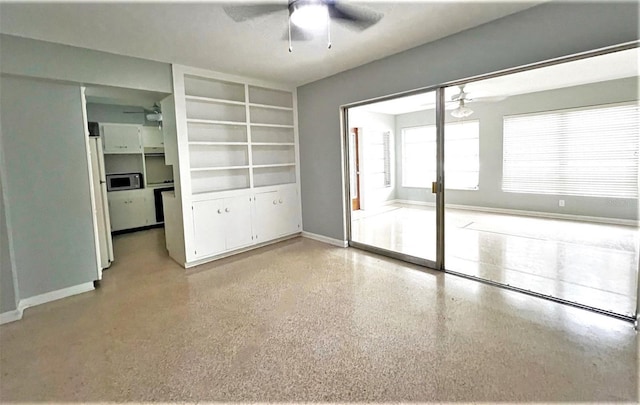 spare room with light speckled floor, baseboards, and ceiling fan
