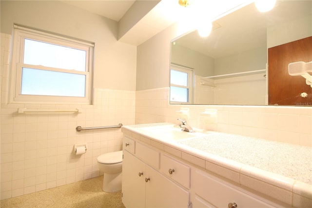 bathroom with tile walls, a wainscoted wall, a shower, toilet, and vanity