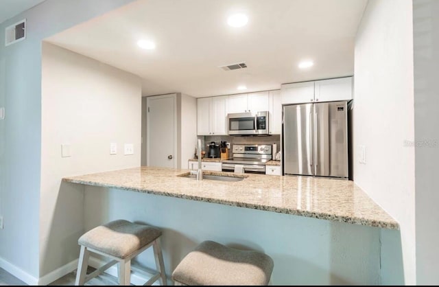 kitchen featuring a sink, visible vents, stainless steel appliances, and a peninsula