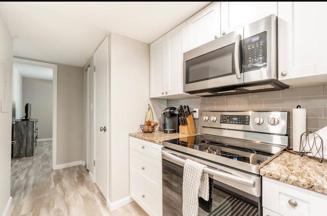 kitchen with white cabinetry, stainless steel appliances, tasteful backsplash, and light stone counters