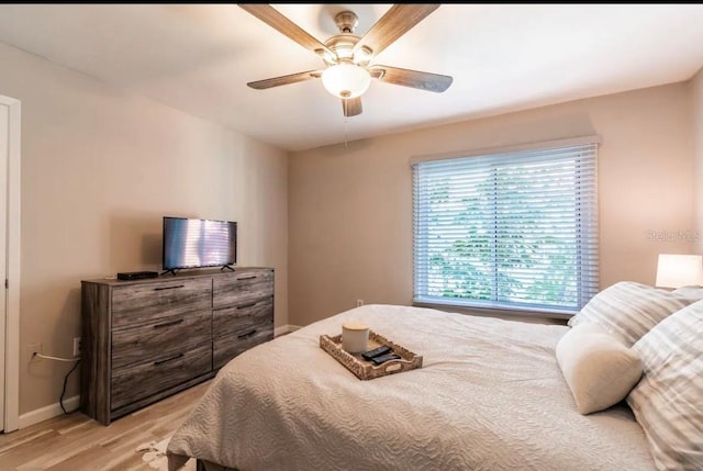 bedroom featuring light wood finished floors, baseboards, and ceiling fan