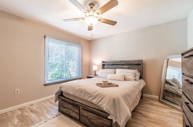 bedroom featuring baseboards, light wood-type flooring, and a ceiling fan