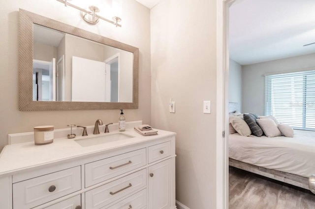bathroom featuring baseboards, ensuite bath, wood finished floors, and vanity