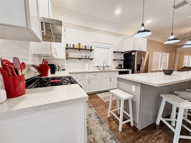 1515 E 31st Ave, Tampa, FL 33610 - kitchen featuring open shelves, wood finished floors, a kitchen bar, stainless steel appliances, and decorative backsplash