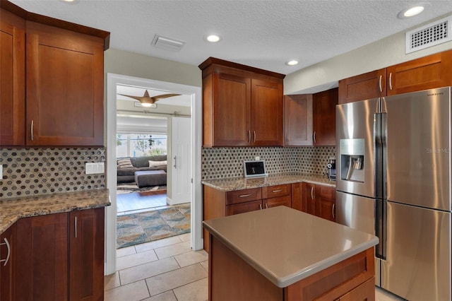 kitchen featuring backsplash, stainless steel refrigerator with ice dispenser, a textured ceiling, and visible vents