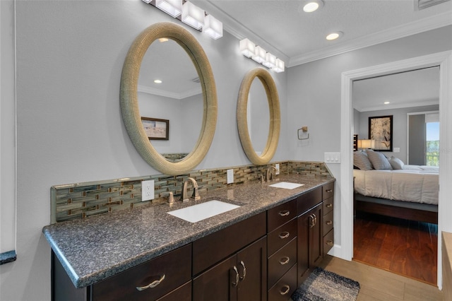 full bathroom featuring ensuite bathroom, backsplash, a sink, and crown molding