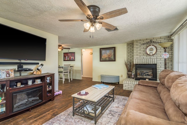 6831 Greenwich Ave, New Port Richey, FL 34653 - living room featuring a brick fireplace, a textured ceiling, visible vents, a ceiling fan, and wood finished floors