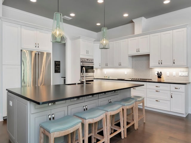 150 Chippewa Ave, Tampa, FL 33606 - kitchen with an island with sink, stainless steel appliances, backsplash, and dark countertops