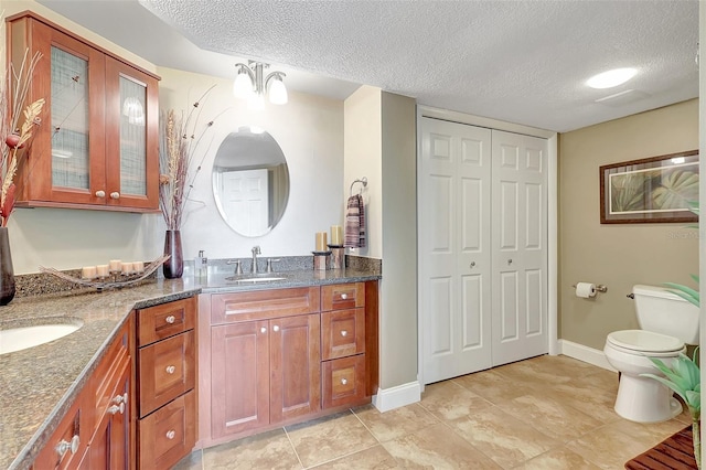 full bath with vanity, a closet, toilet, and a textured ceiling