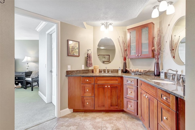 full bathroom featuring baseboards, double vanity, a textured ceiling, and a sink