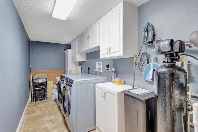 laundry area featuring baseboards, a textured ceiling, separate washer and dryer, cabinet space, and light tile patterned floors