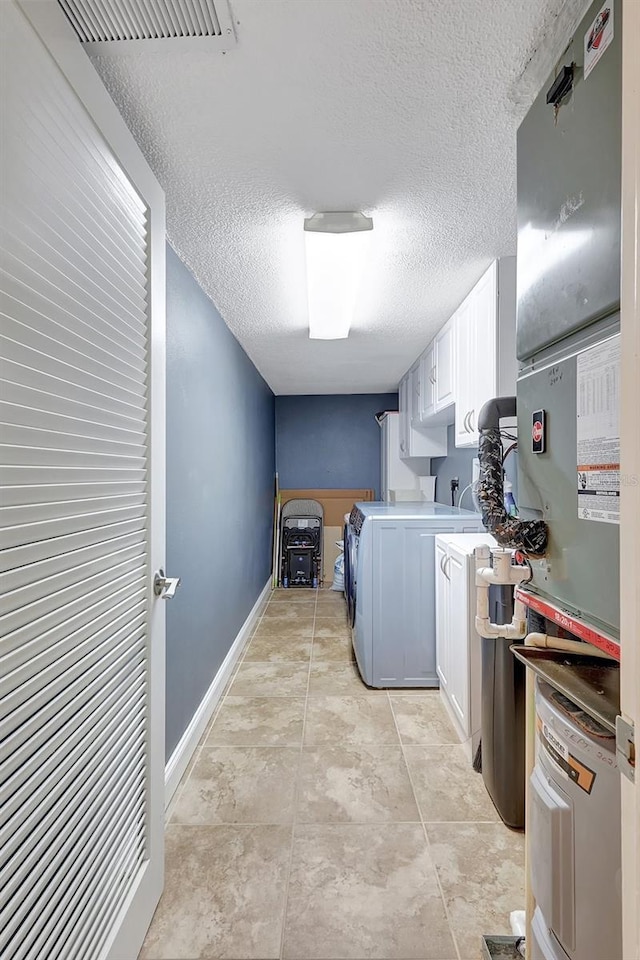 clothes washing area with cabinet space, independent washer and dryer, a textured ceiling, and baseboards