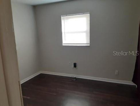 empty room featuring baseboards and dark wood-style flooring