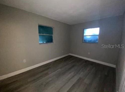 empty room featuring dark wood-style flooring and baseboards