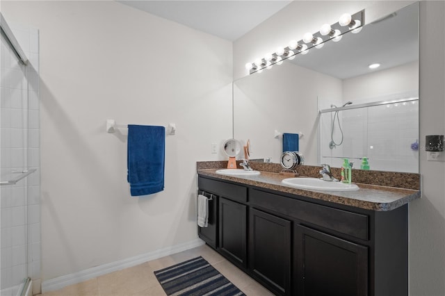 bathroom with a sink, tile patterned floors, a tile shower, and double vanity