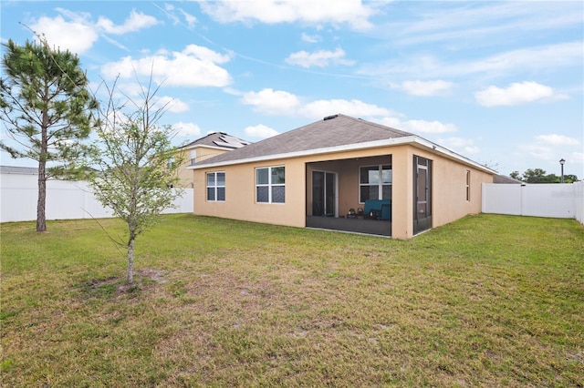 back of house with a sunroom, a fenced backyard, stucco siding, and a lawn