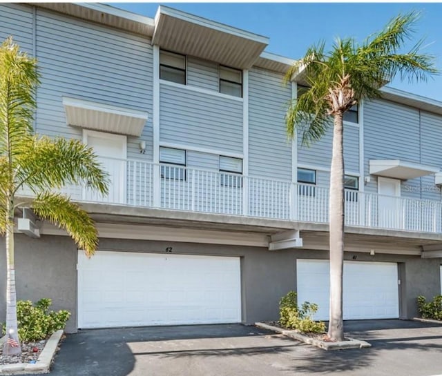 townhome / multi-family property with stucco siding, an attached garage, and aphalt driveway