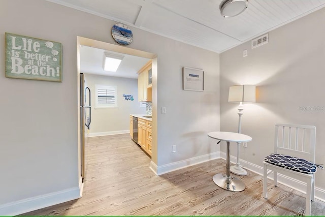 interior space featuring light wood finished floors, baseboards, and visible vents