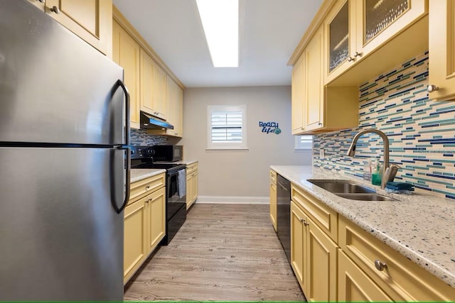 kitchen with black appliances, under cabinet range hood, a sink, and decorative backsplash