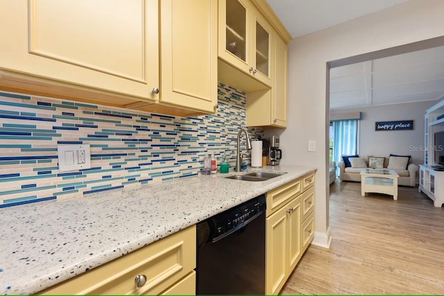 kitchen with light wood-style floors, a sink, tasteful backsplash, dishwasher, and cream cabinetry