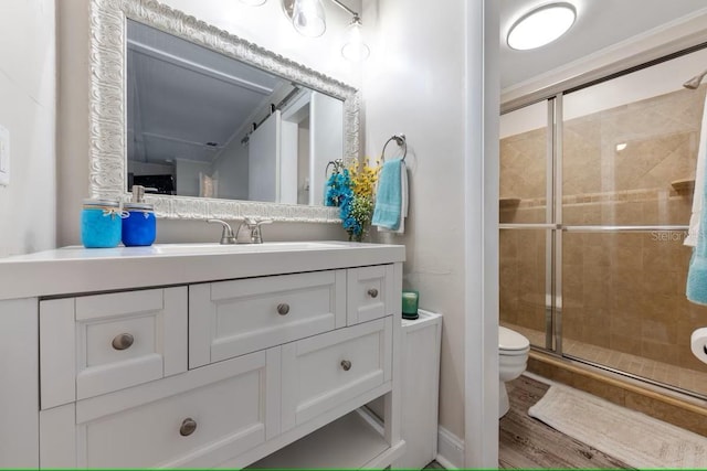 bathroom featuring a stall shower, wood finished floors, toilet, and vanity